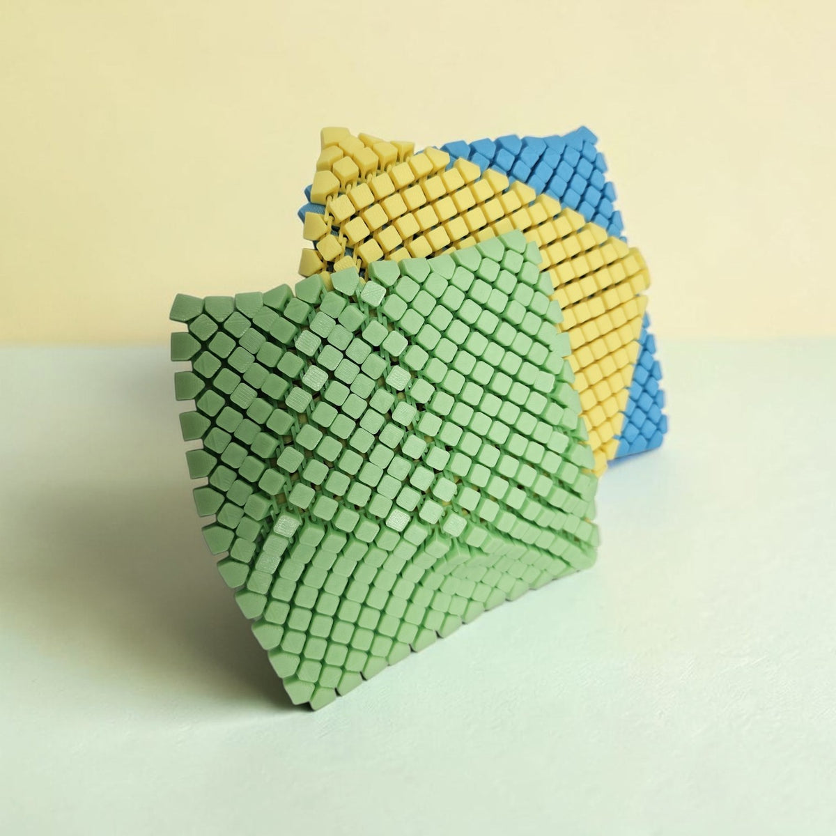 Made In Cobham set of flexible 3D-printed square coasters in green, yellow, and blue with a tactile grid pattern.