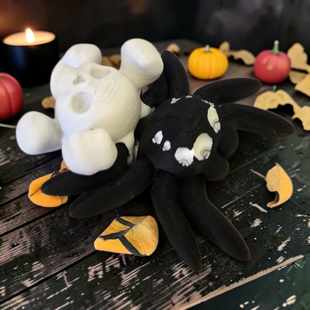 Made In Cobham 3D-printed black spider figurine with a white skull accent, displayed on a rustic Halloween table.