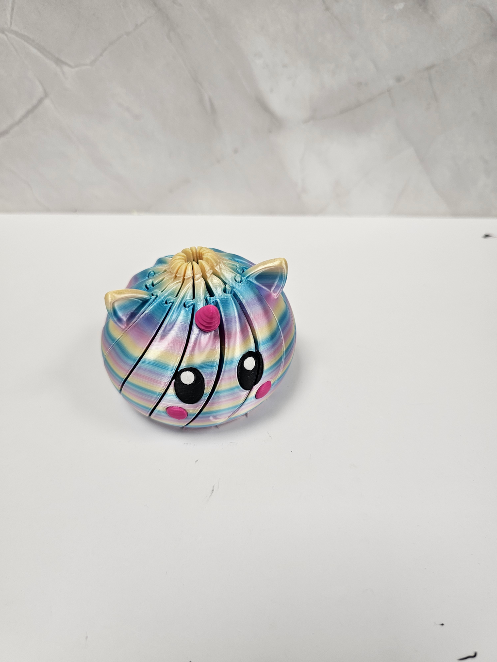 Made In Cobham articulated unicorn fidget sphere with a rainbow gradient finish and cute expressive face.
